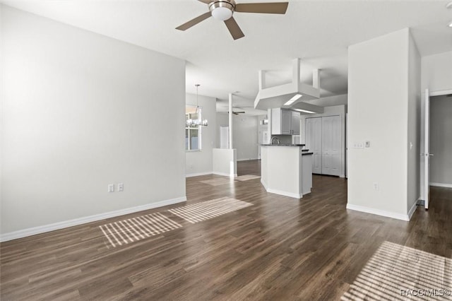 unfurnished living room with baseboards, dark wood-style flooring, and ceiling fan with notable chandelier