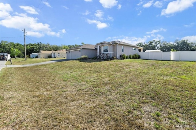 exterior space with stucco siding, fence, driveway, and a front lawn