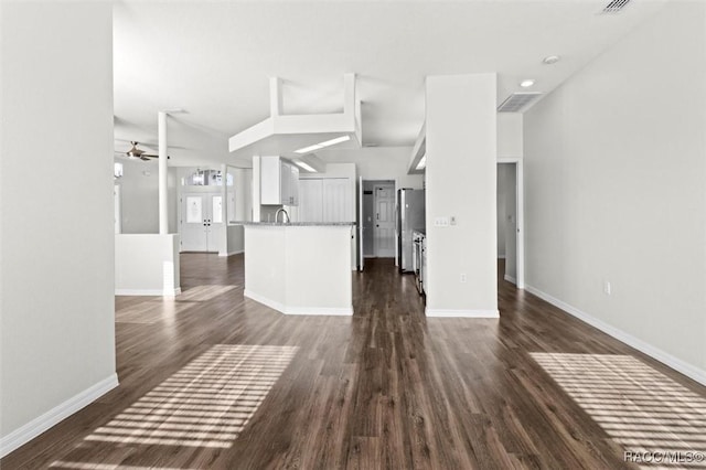 unfurnished living room with vaulted ceiling, baseboards, a ceiling fan, and dark wood finished floors