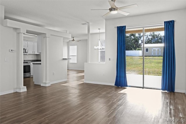 unfurnished living room with baseboards, plenty of natural light, ceiling fan with notable chandelier, and dark wood finished floors
