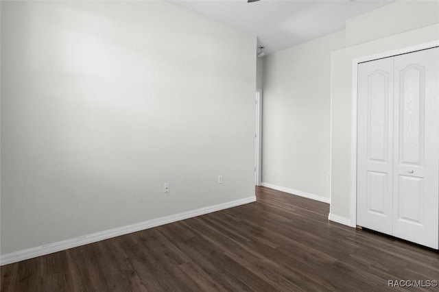 unfurnished bedroom with baseboards, ceiling fan, a closet, and dark wood finished floors
