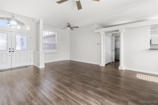 unfurnished living room featuring baseboards, dark wood-style floors, french doors, and ceiling fan with notable chandelier