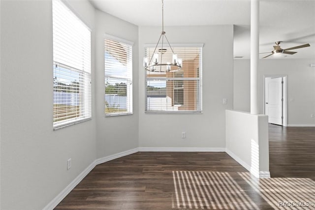 unfurnished dining area featuring baseboards, dark wood finished floors, and ceiling fan with notable chandelier