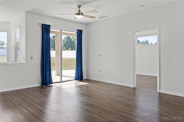 unfurnished room with visible vents, a ceiling fan, dark wood finished floors, and baseboards