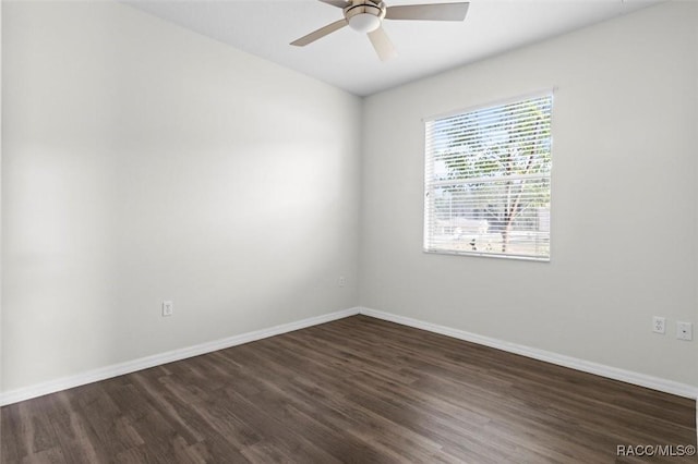 spare room with baseboards, ceiling fan, and dark wood-type flooring