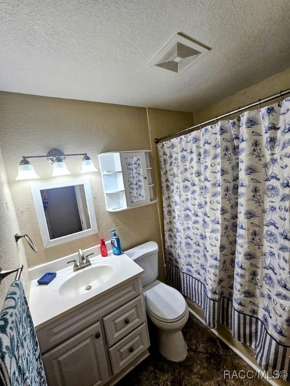 full bathroom featuring toilet, vanity, a textured ceiling, and shower / bath combo with shower curtain