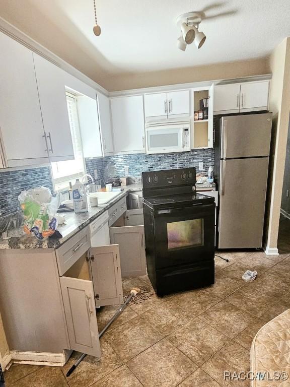 kitchen with black range with electric stovetop, decorative backsplash, stainless steel refrigerator, sink, and white cabinetry