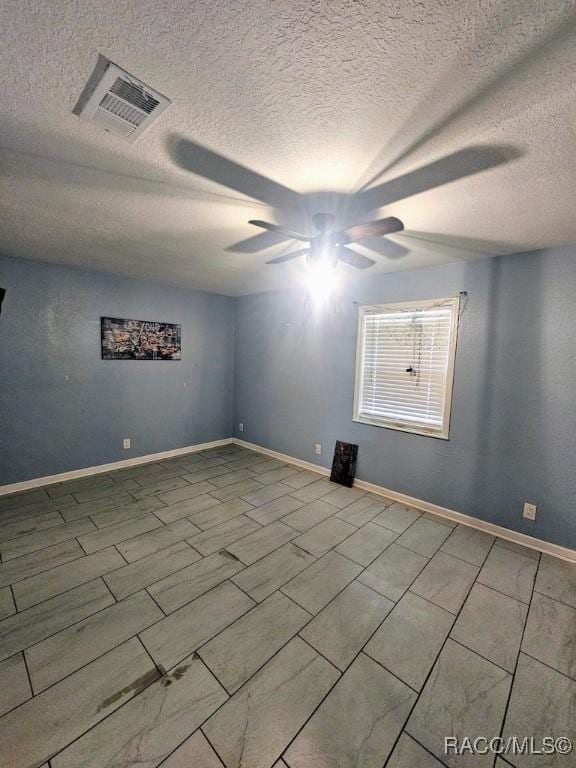 unfurnished room with ceiling fan and a textured ceiling