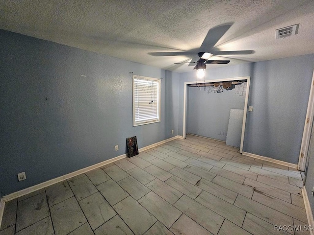 unfurnished room with ceiling fan and a textured ceiling