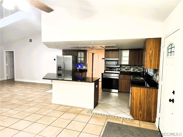 kitchen with vaulted ceiling, decorative backsplash, ceiling fan, light tile patterned flooring, and stainless steel appliances