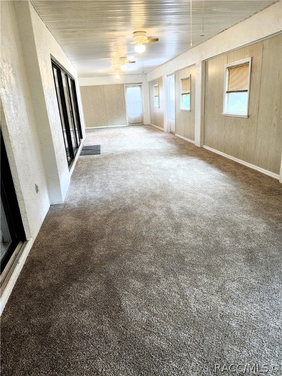 unfurnished living room featuring carpet flooring, ceiling fan, and a healthy amount of sunlight