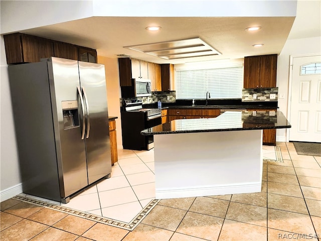 kitchen with decorative backsplash, sink, a kitchen island, and appliances with stainless steel finishes