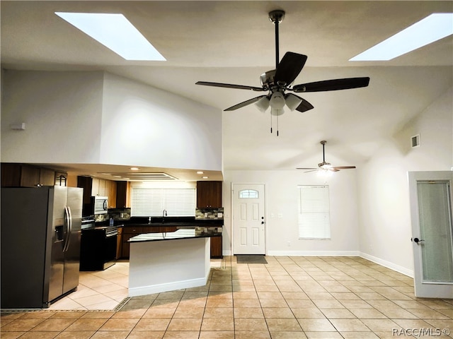 kitchen with ceiling fan, sink, high vaulted ceiling, light tile patterned floors, and appliances with stainless steel finishes