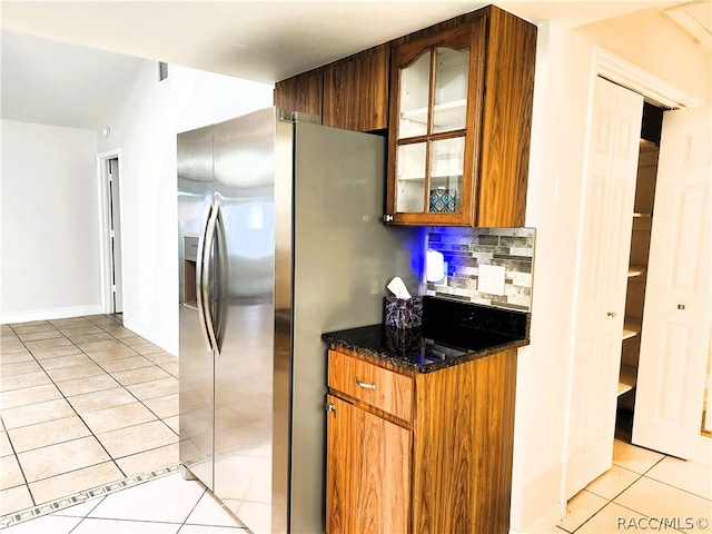 kitchen featuring stainless steel fridge, light tile patterned floors, and backsplash