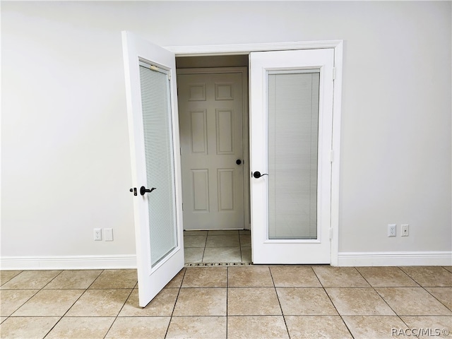 unfurnished bedroom with light tile patterned floors, french doors, and a closet