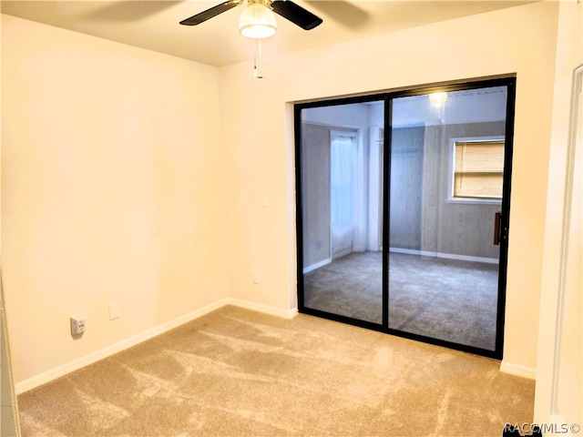 unfurnished bedroom featuring ceiling fan, light colored carpet, and a closet