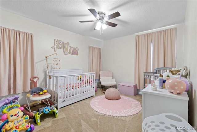 carpeted bedroom featuring a crib, a textured ceiling, and ceiling fan