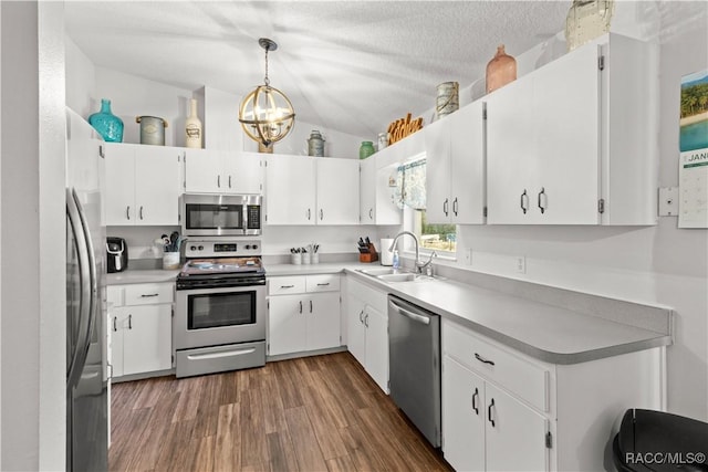 kitchen featuring sink, white cabinets, decorative light fixtures, vaulted ceiling, and appliances with stainless steel finishes