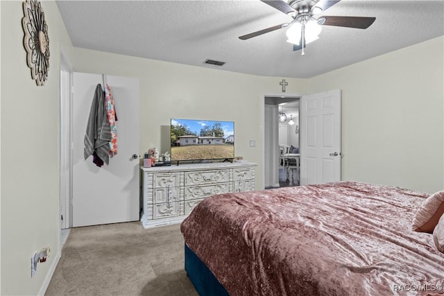 bedroom featuring light colored carpet, ceiling fan, and a textured ceiling