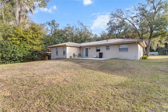 back of house with a patio and a lawn