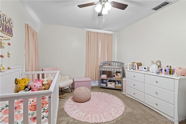 carpeted bedroom with ceiling fan and a textured ceiling