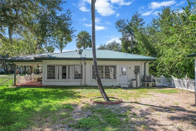 rear view of property featuring a yard, metal roof, central air condition unit, and fence