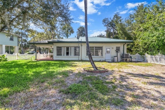 back of house featuring fence, cooling unit, metal roof, and a lawn