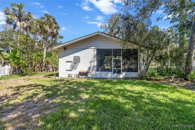 exterior space featuring a yard, fence, and a sunroom