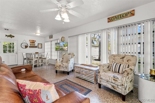 living area with speckled floor, ceiling fan, visible vents, and baseboards