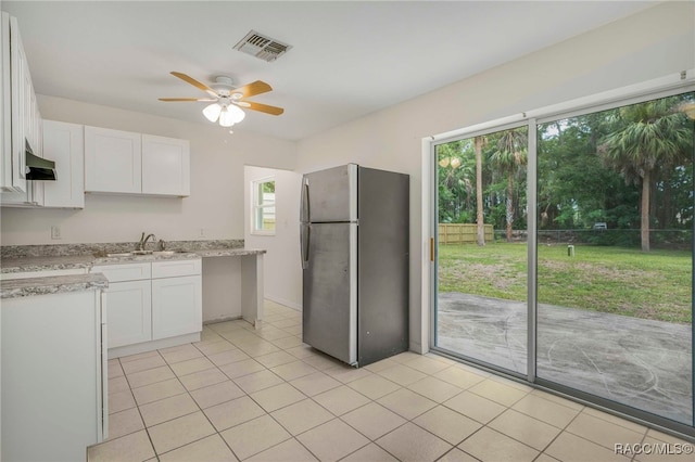 3410 N Bay Ave, Crystal River, FL 34428 - kitchen with freestanding refrigerator, white cabinets, a ceiling fan, and light tile patterned floors
