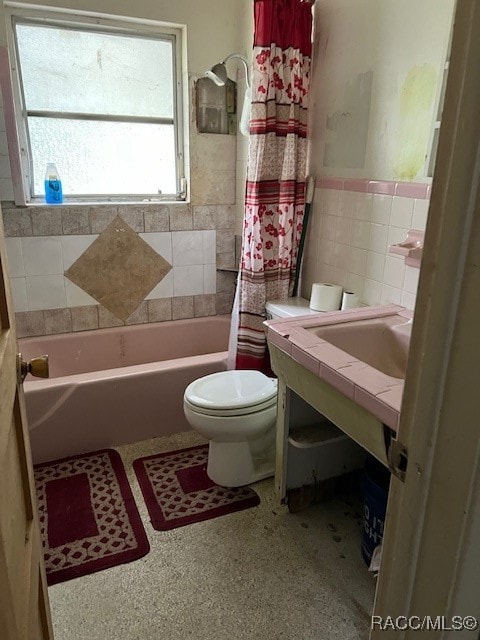 bathroom featuring shower / bath combo, tile walls, and toilet