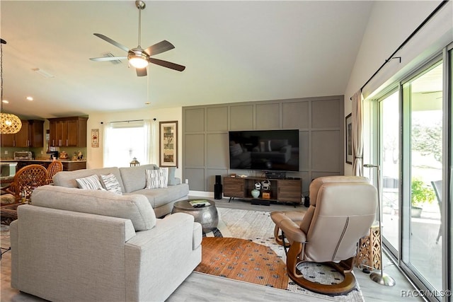 living area featuring light wood-style floors, a ceiling fan, and vaulted ceiling