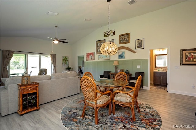 dining room featuring visible vents, ceiling fan with notable chandelier, high vaulted ceiling, and light wood-style flooring