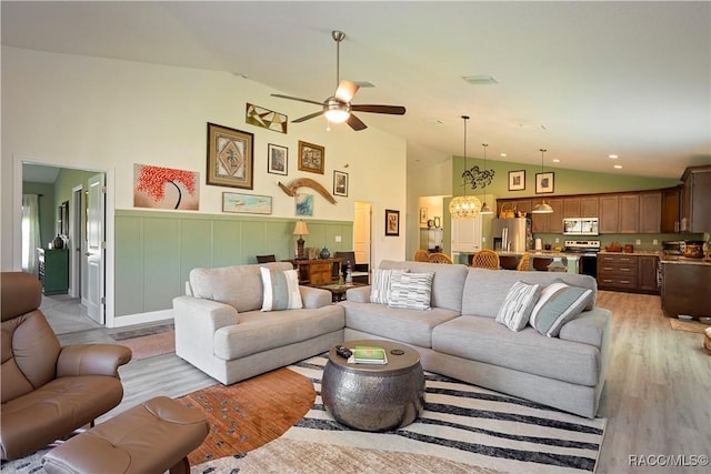 living area featuring visible vents, high vaulted ceiling, light wood-style flooring, and ceiling fan with notable chandelier