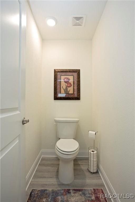 bathroom featuring visible vents, toilet, wood finished floors, and baseboards