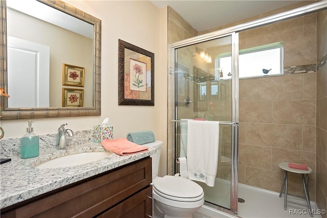 bathroom with a shower stall, vanity, and toilet