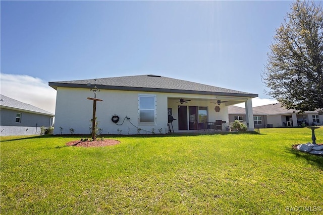 back of house featuring stucco siding, a yard, and ceiling fan