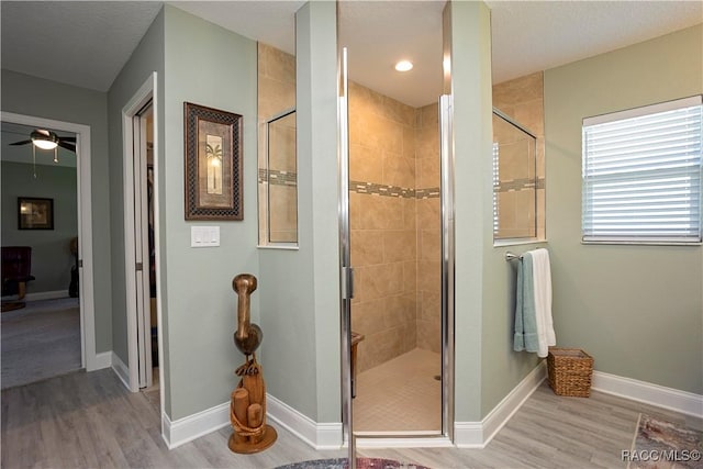 full bath with a shower stall, wood finished floors, and baseboards