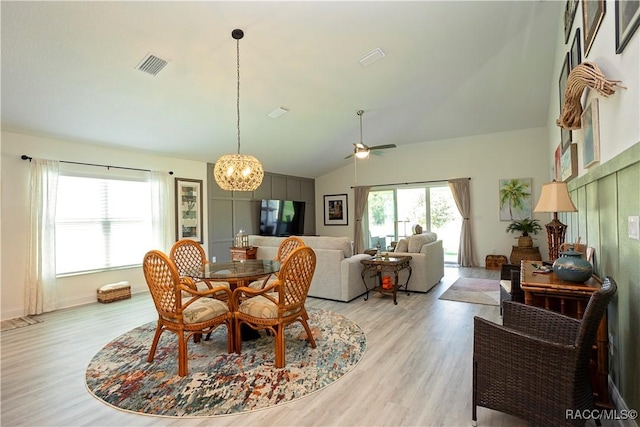 dining room featuring lofted ceiling, ceiling fan with notable chandelier, visible vents, and light wood finished floors