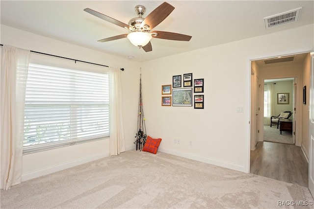 spare room with visible vents, carpet flooring, baseboards, and a ceiling fan