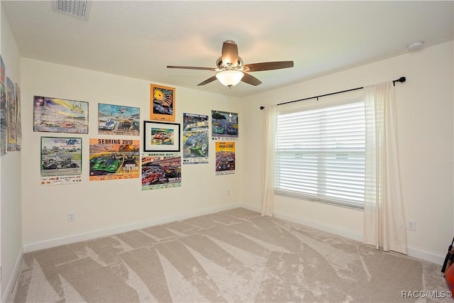 spare room with visible vents, baseboards, light colored carpet, and a ceiling fan