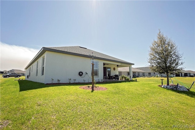 back of house featuring a lawn, a patio, a ceiling fan, and stucco siding