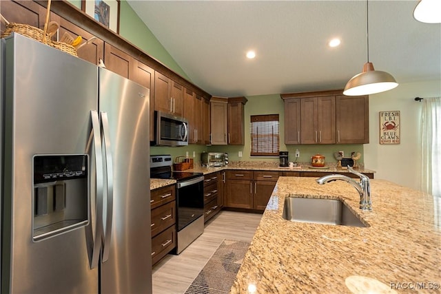 kitchen with light wood-style flooring, a sink, stainless steel appliances, vaulted ceiling, and decorative light fixtures