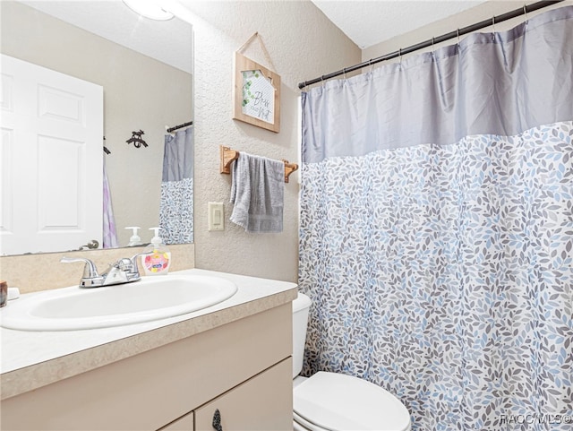 bathroom with vanity, toilet, curtained shower, and a textured ceiling