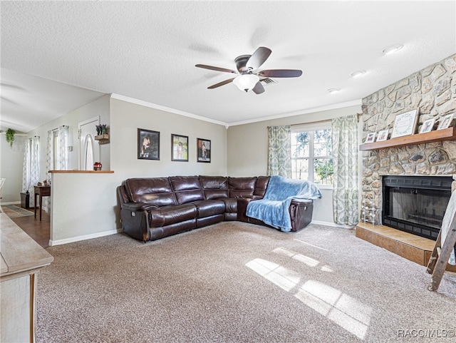 carpeted living room with crown molding, ceiling fan, a stone fireplace, and a textured ceiling