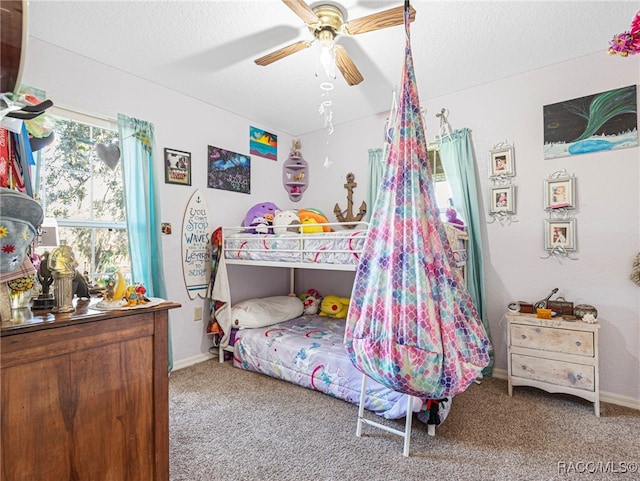 carpeted bedroom featuring ceiling fan and a textured ceiling