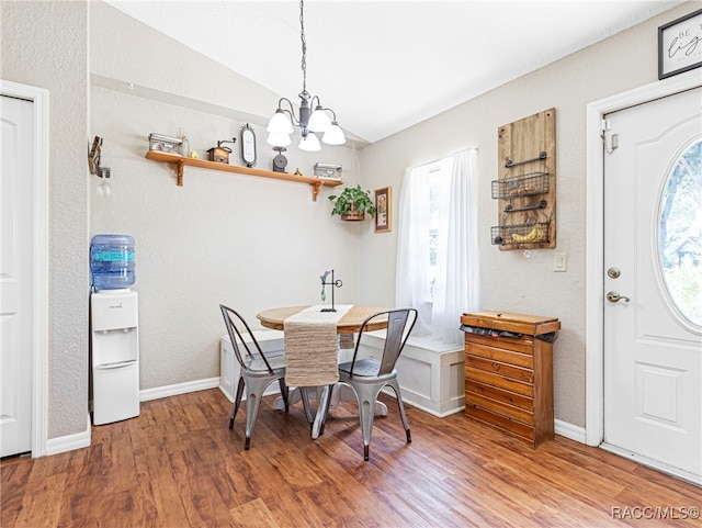 dining area featuring lofted ceiling, a notable chandelier, and wood-type flooring