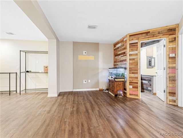 unfurnished living room with hardwood / wood-style floors and wood walls