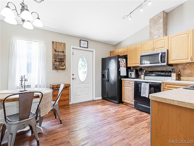 kitchen with vaulted ceiling, electric range oven, decorative backsplash, hanging light fixtures, and black fridge