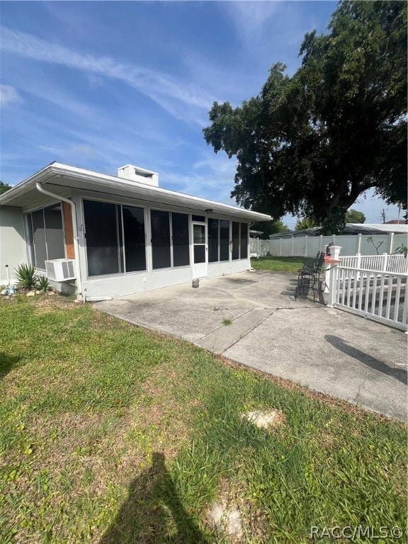 back of property with a lawn, a patio area, and a sunroom